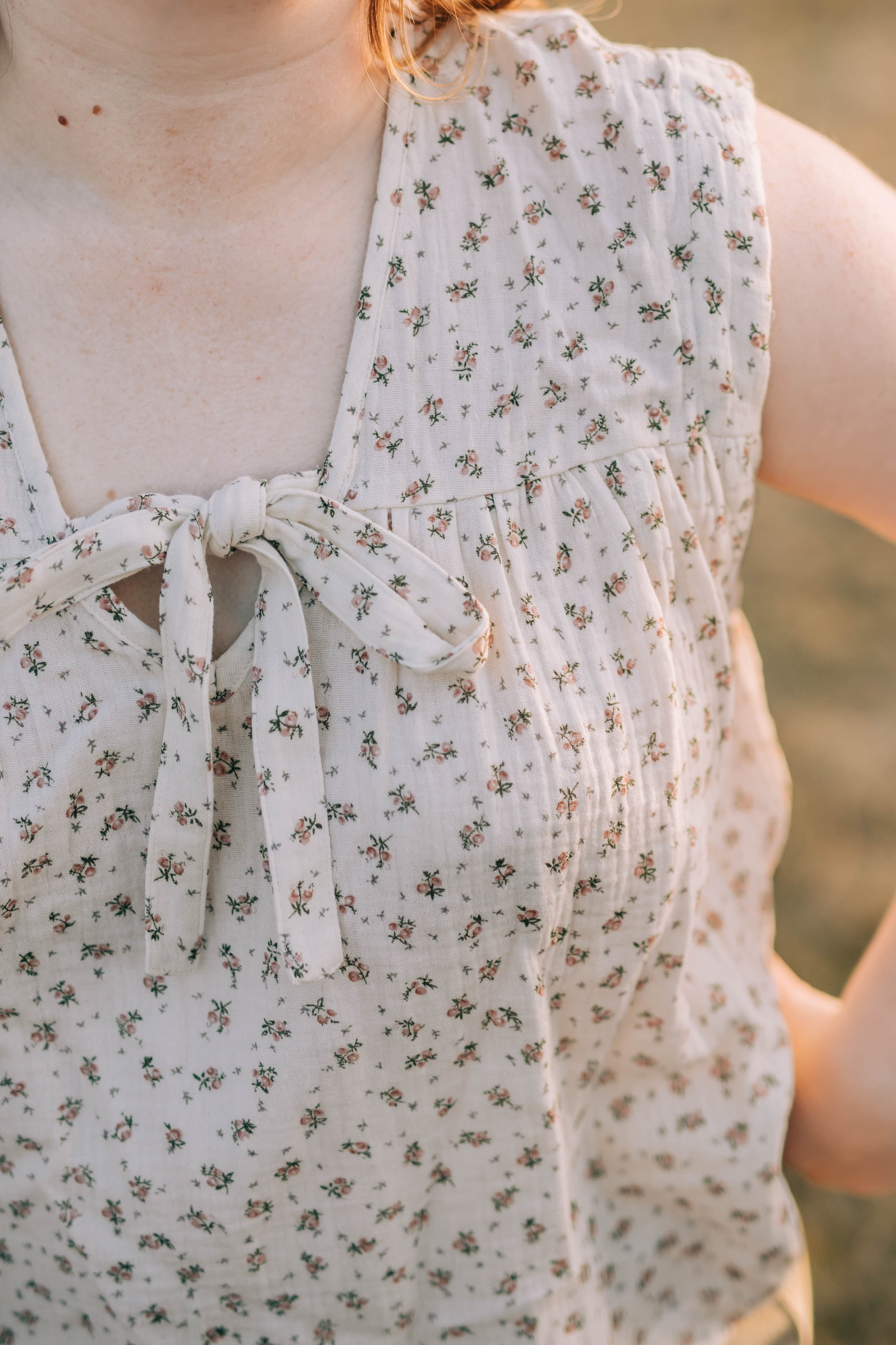 Closeup of the Molly top which is a 100% cotton, cap sleeve top. The Molly top is cream with a small pink and green floral print. 