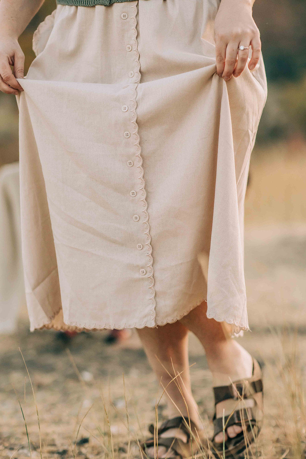 Person wearing a beige skirt with buttons in an outdoor setting